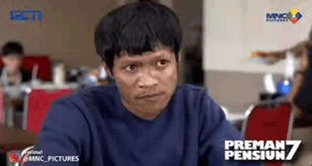 a man is sitting at a table in a restaurant making a funny face .