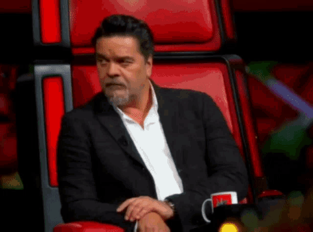 a man with a beard is sitting in a red chair