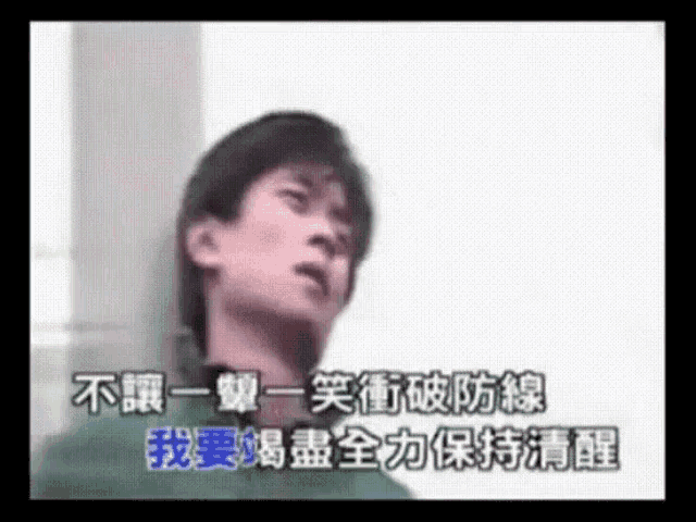 a man is leaning against a wall and singing in chinese .