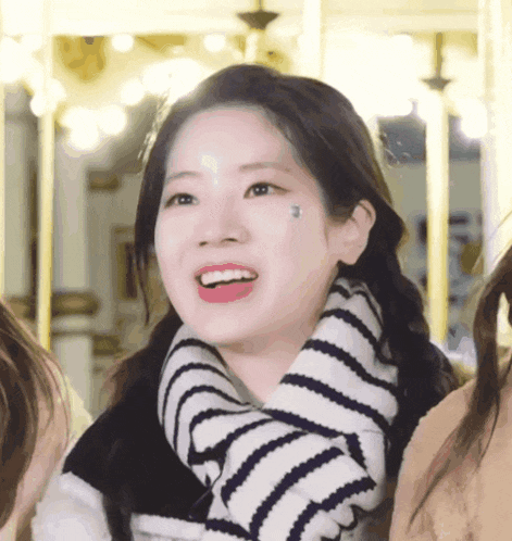 a woman wearing a striped scarf around her neck is smiling