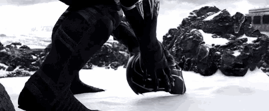 a black panther is standing in the snow with a helmet on .