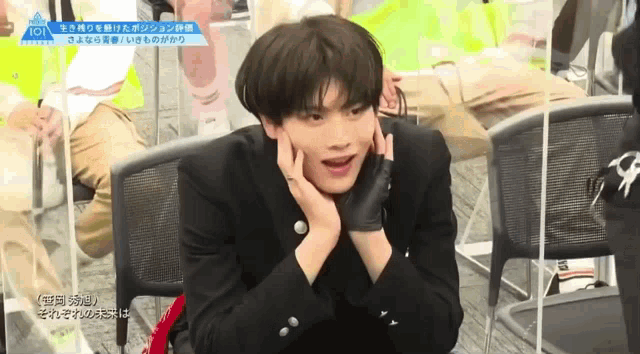 a young man is sitting in a chair with his hands on his face and his mouth open .