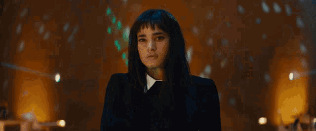 a woman with long hair and bangs is standing in front of a crowd