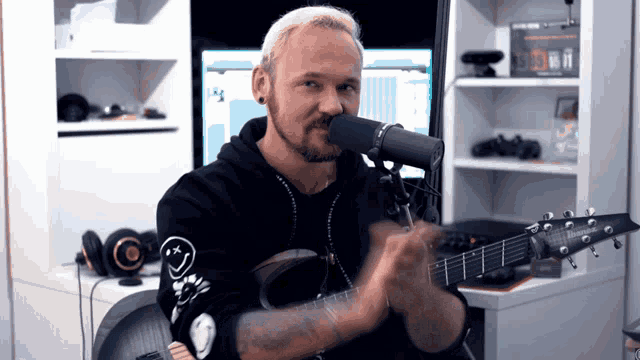 a man playing a guitar in front of a microphone