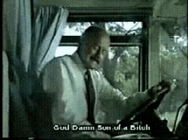 a man in a suit and tie says god damn son of a bitch while looking out a window