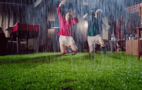 two people are jumping in the rain with their arms up