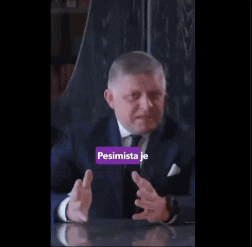 a man in a suit and tie is sitting at a table with his hands outstretched and the words dobre informovany above him
