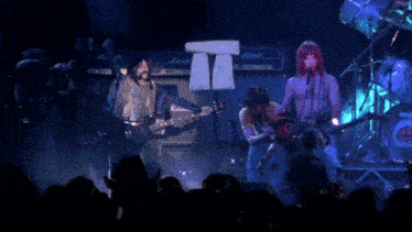 a group of people playing instruments on a stage with marshall amps in the background