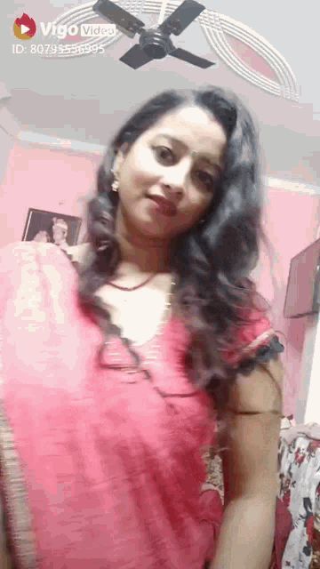 a woman in a red dress is standing in a room with a ceiling fan .