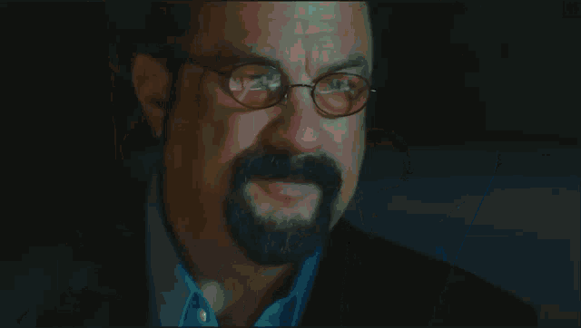 a man with a beard wearing glasses and a suit