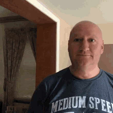 a bald man wearing a medium speed t-shirt