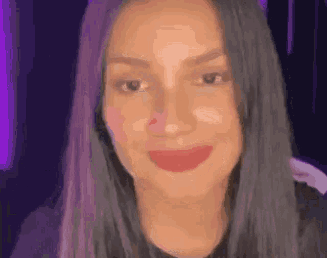 a close up of a woman 's face with purple hair smiling .