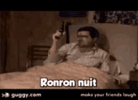 a man is laying in bed holding a gun and the words ronron nuit are on the screen