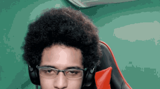 a man wearing glasses and headphones sits in a chair
