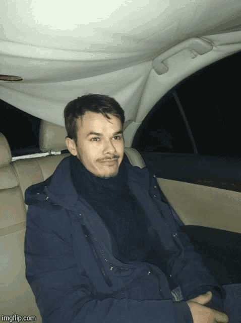a man is sitting in the back seat of a car with imgflip.com written on the bottom right