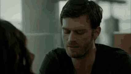 a man with a beard is talking to a woman while sitting at a table .
