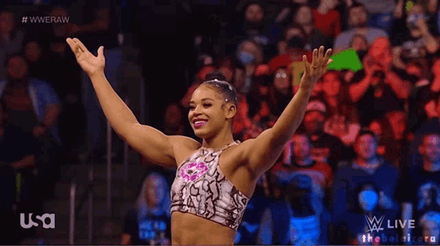 a female wrestler stands in front of a crowd with her arms in the air and a usa logo in the corner