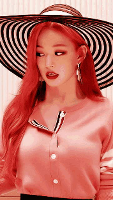 a woman with red hair wearing a pink shirt and a striped hat