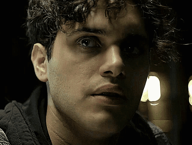 a man with curly hair is looking at the camera