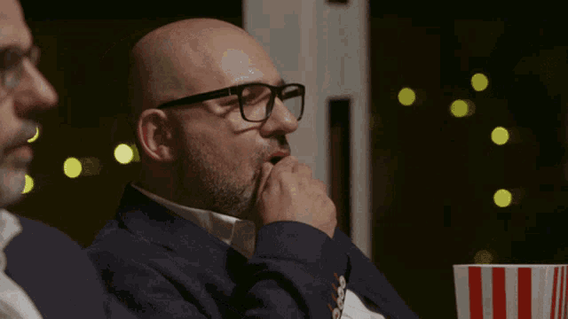 a bald man wearing glasses sits next to a man with a beard