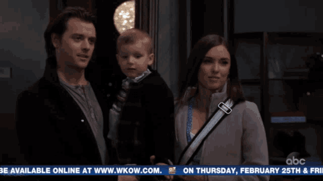 a man and woman holding a child in front of a abc news headline