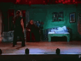 a man is dancing on a stage in front of a green wall
