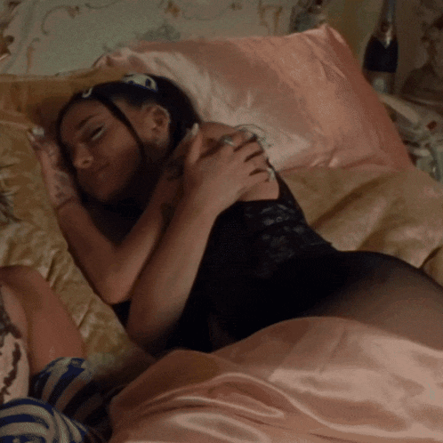 a woman in a black lace bodysuit is sleeping on a bed