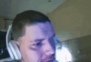 a man wearing headphones looks at the camera with a purple background