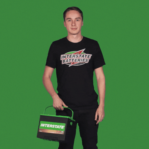 a man wearing a black shirt that says interstate batteries is holding a battery