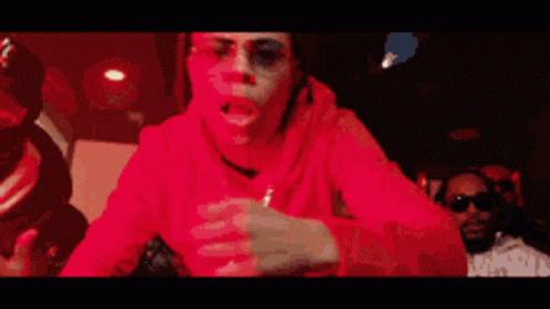 a woman in a red hoodie is standing in a kitchen in front of a red light .