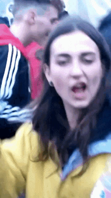 a woman in a yellow jacket is making a funny face with her mouth open