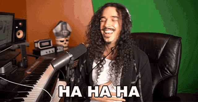 a man with long curly hair is laughing in front of a microphone with ha ha ha written on the bottom