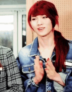 a woman with red hair wearing a denim jacket applauds