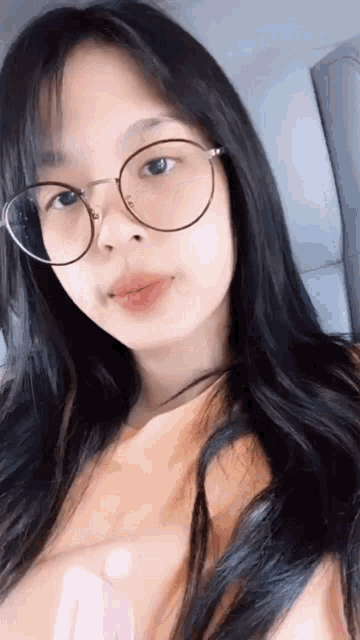 a close up of a woman wearing glasses and a pink shirt .