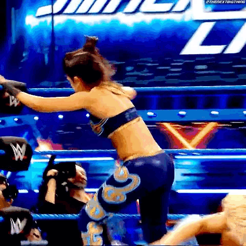 a woman is standing in a wrestling ring with a wwe logo in the background