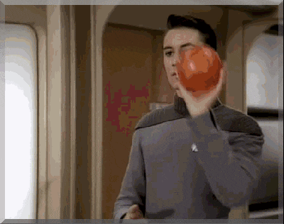 a man in a grey jacket is holding a red apple in his hand