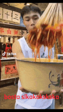 a man is holding a large bowl of food with the words bosta slikakakska written on the bottom