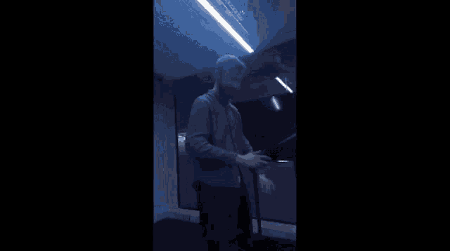 a man with a beard is standing in a dark room with a blue light on the ceiling