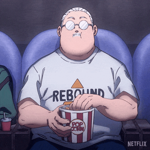 a man in a rebound shirt is eating popcorn in a movie theater