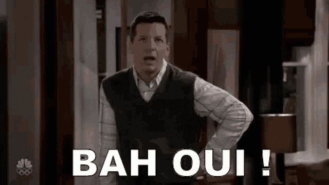 a man is standing in a room with his hands on his hips and says bah oui .