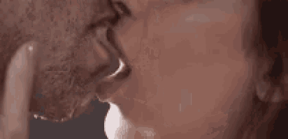 a man and a woman are kissing each other in a close up of their mouths .