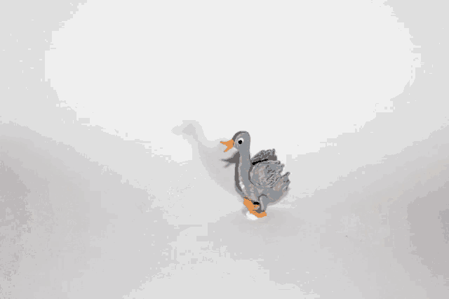 a white duck and a grey duck are standing next to each other on a white surface