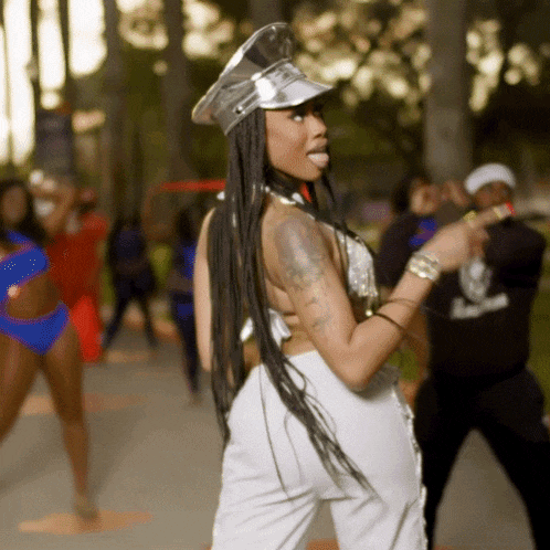 a woman wearing a silver hat and white pants is dancing