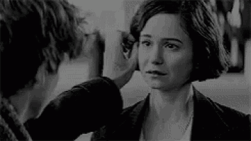 a man is touching the ear of a woman in a black and white photo .