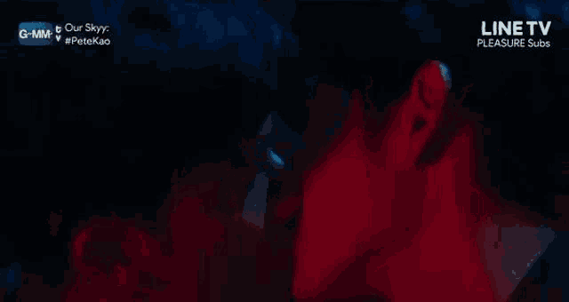 two men are kissing each other in a dark room with a red light behind them .