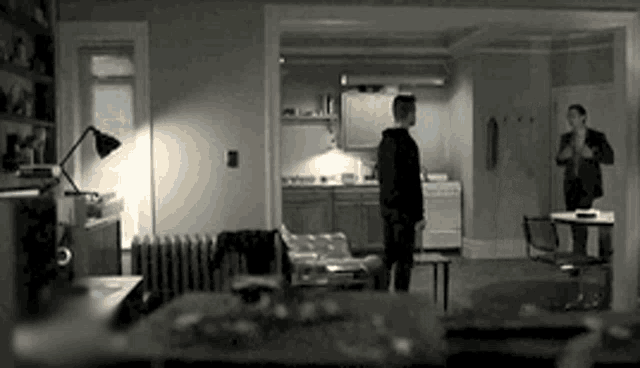 a black and white photo of a living room with a man standing in the middle of it