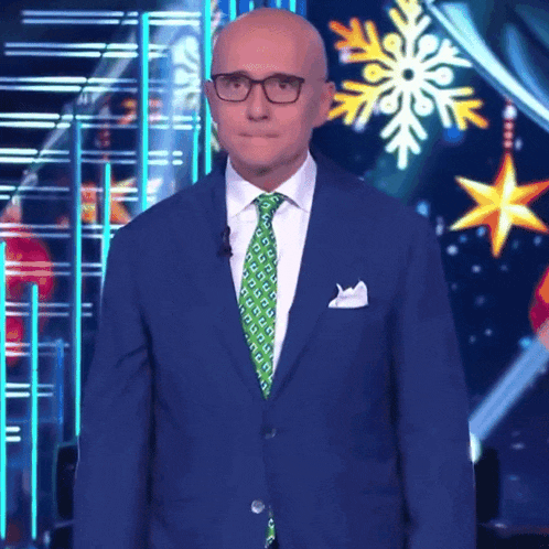 a man in a blue suit and green tie is standing in front of a snowflake