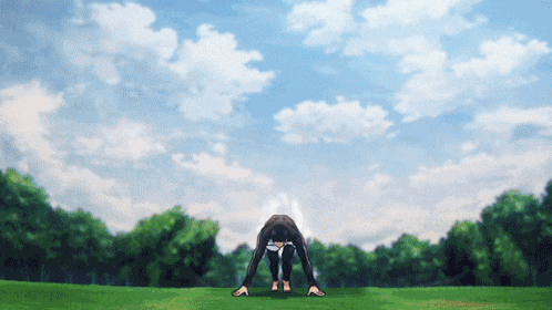 a person bending over in a field with trees in the background and a blue sky with clouds