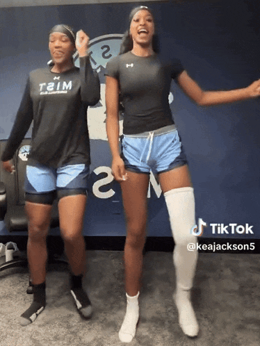 two female athletes are dancing in front of a wall that has the number 2 on it