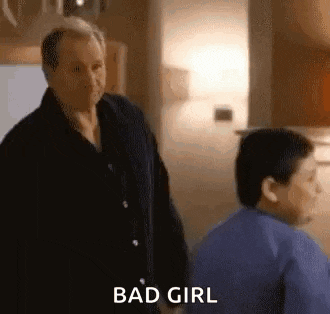a man and a boy are standing next to each other in a room . the man is saying `` bad girl '' .